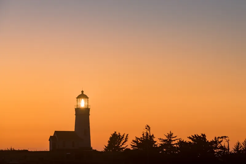 Cape Blanco Lighthouse silhouetted against an orange sky