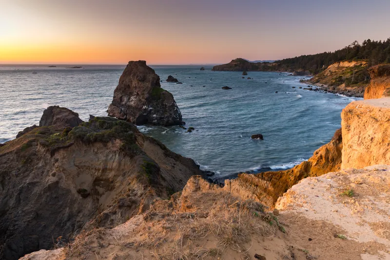 Sandstone headlands and offshore rocks at sunset at Otter Point