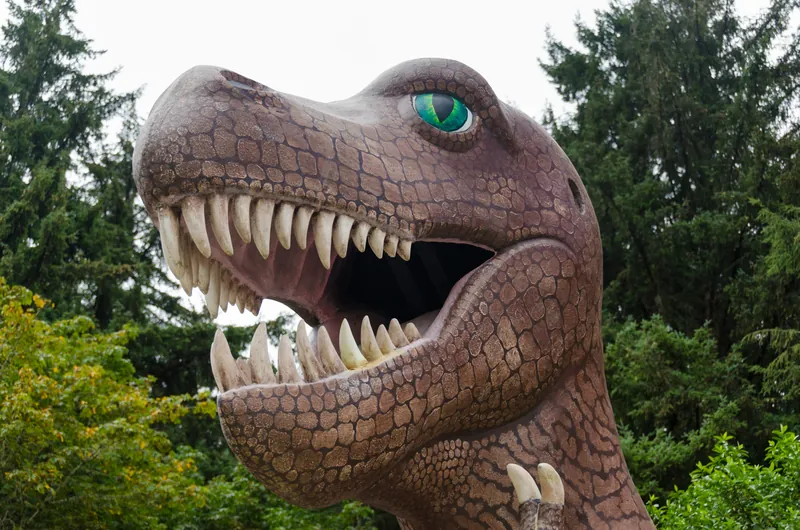 A life-sized dinosaur sculpture among rainforest greenery at Prehistoric Gardens